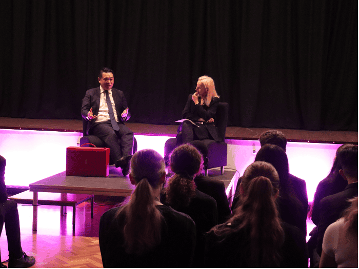 Alan Mak MP on stage at Cheadle Hulme High School, speaking with students about his career journey. 