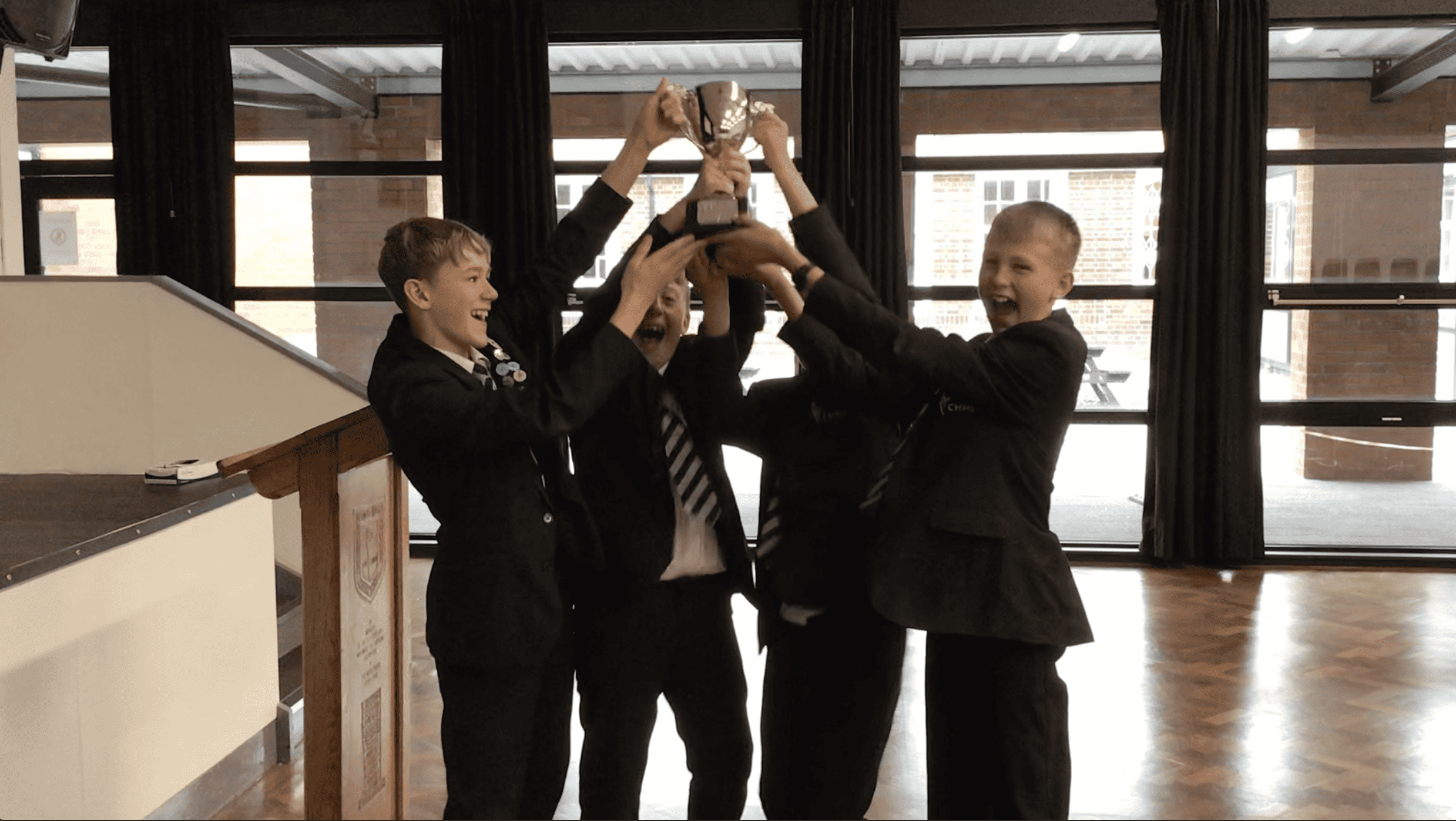 A team of Cheadle Hulme High School students raise the trophy they won at the Maths Varsity.