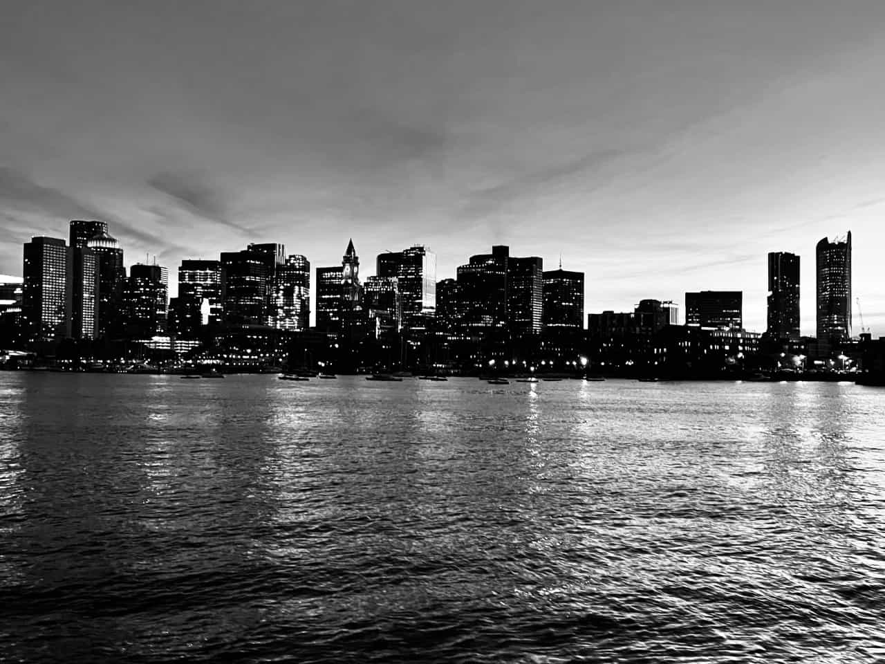 A black and white image of a City Skyline with a body of water in the foreground.