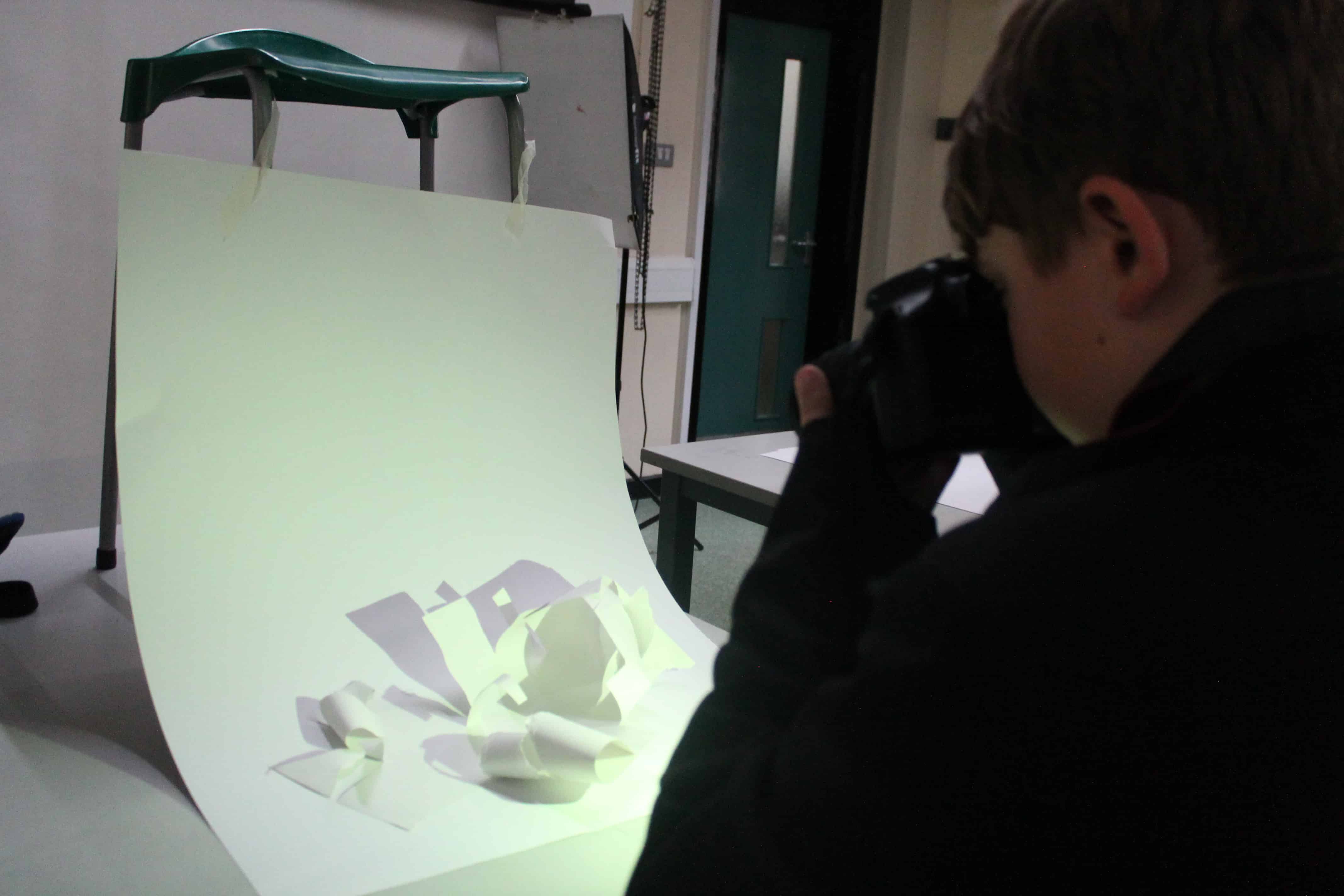 A student from Cheadle Hulme High School takes a photo of their paper sculpture during a workshop for the Big Draw 2023.