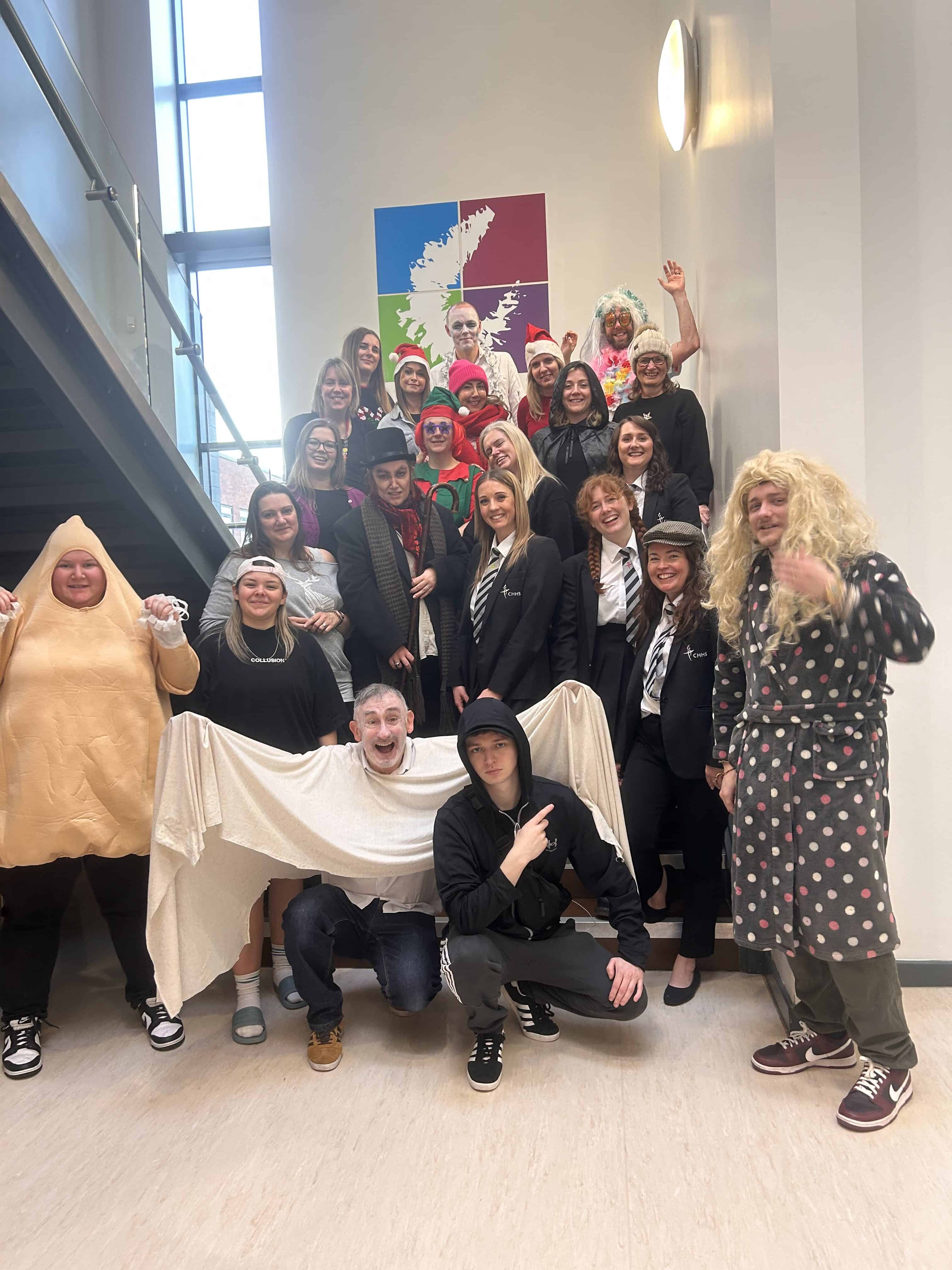 Cheadle Hulme High School and Sixth Form staff pose on the stairs in their pantomime costumes.