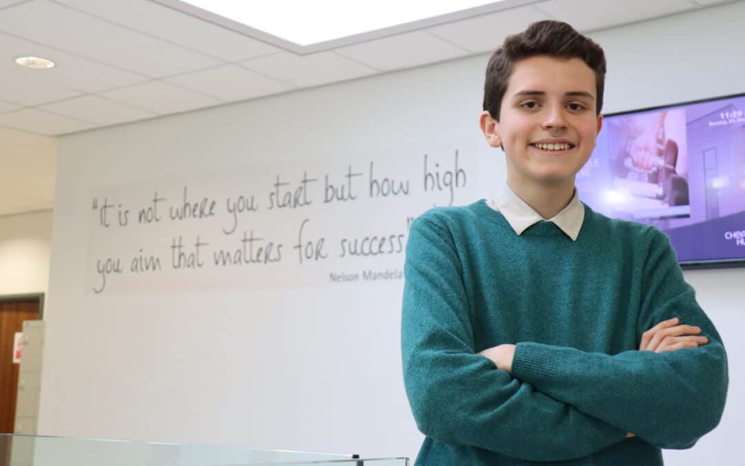 Cheadle Hulme Sixth Form student and Member of UK Youth Parliament, Rodrigo Palmer stands in the Sixth Form building in front of a wall that reads: "It is not where you start but how high you aim that matters for success"