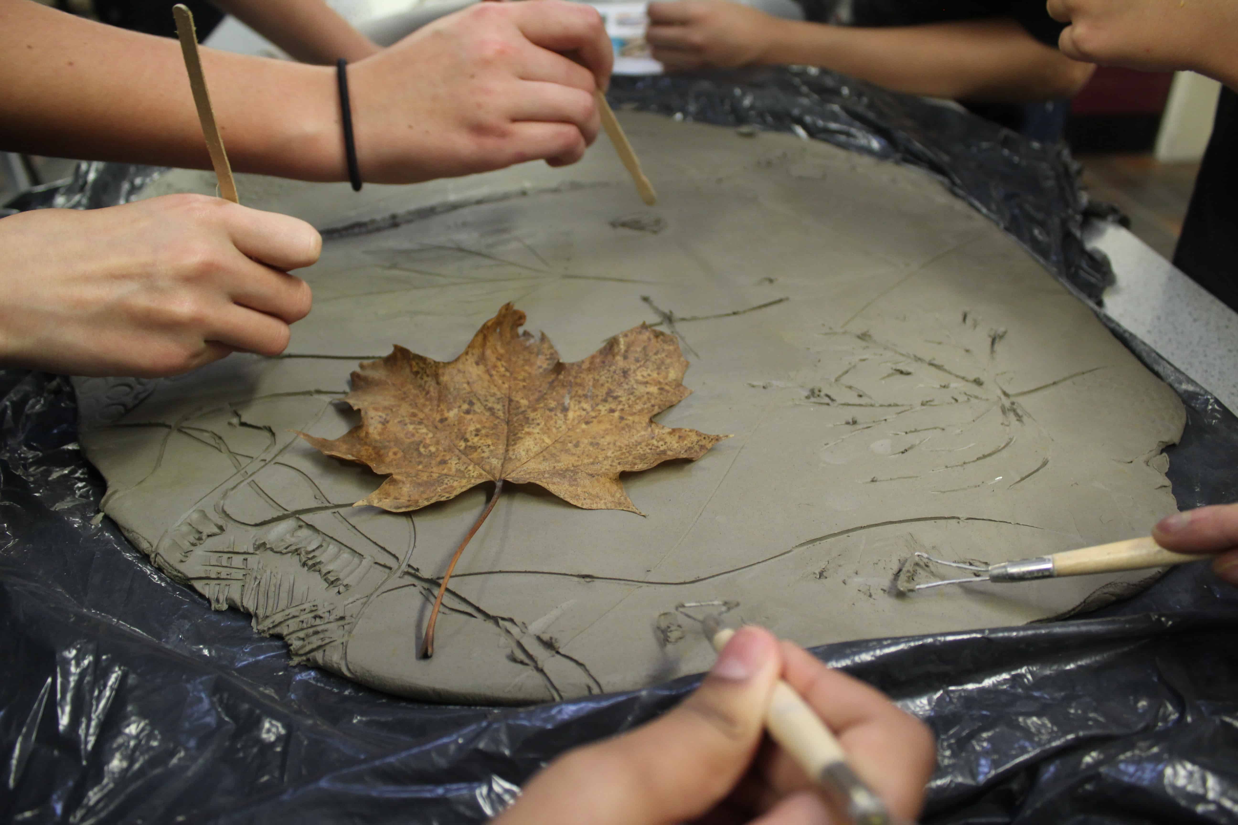 Students from Cheadle Hume High School use tools and a leaf to create their clay tiles in a collaborative clay workshop for the Big Draw 2023.