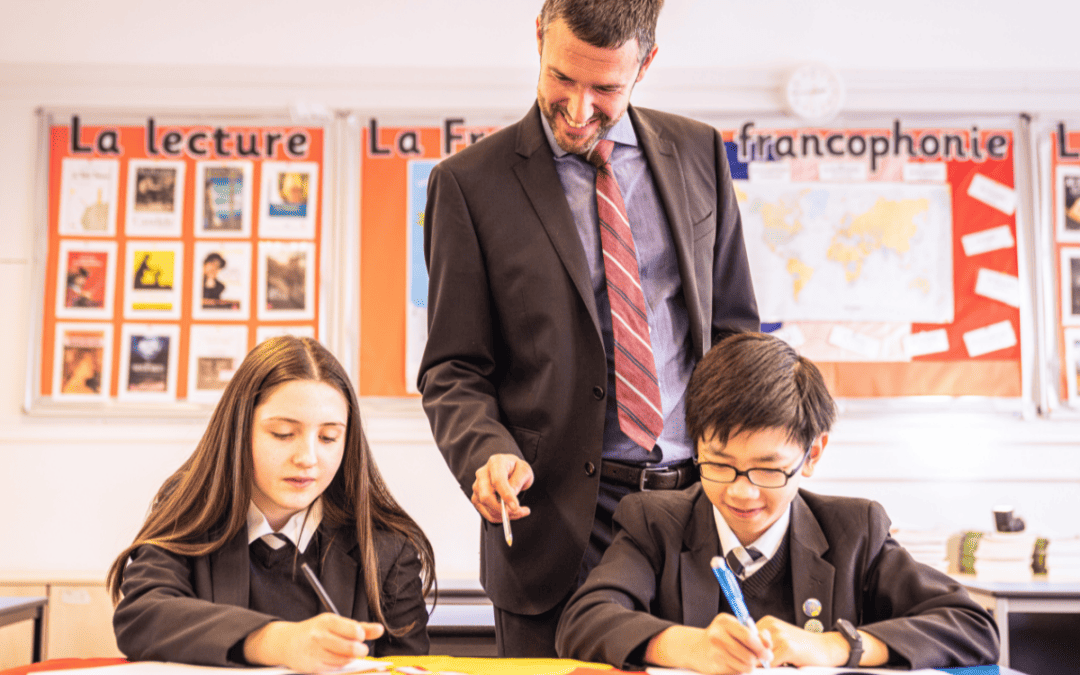 A Languages teacher works with two students from Cheadle Hulme High School in a classroom. Featured: NCLE CHHS becomes a lead Language Hub school.