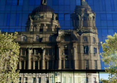 The reflection of a traditional building on the mirrored surface of a modern building. The upper two thirds of the image are dark while the lower third is light.