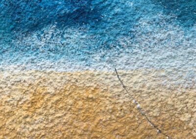 A textured surface with an ombre of colours much like a beach. Ocean blues blend into white then into sandy tones.