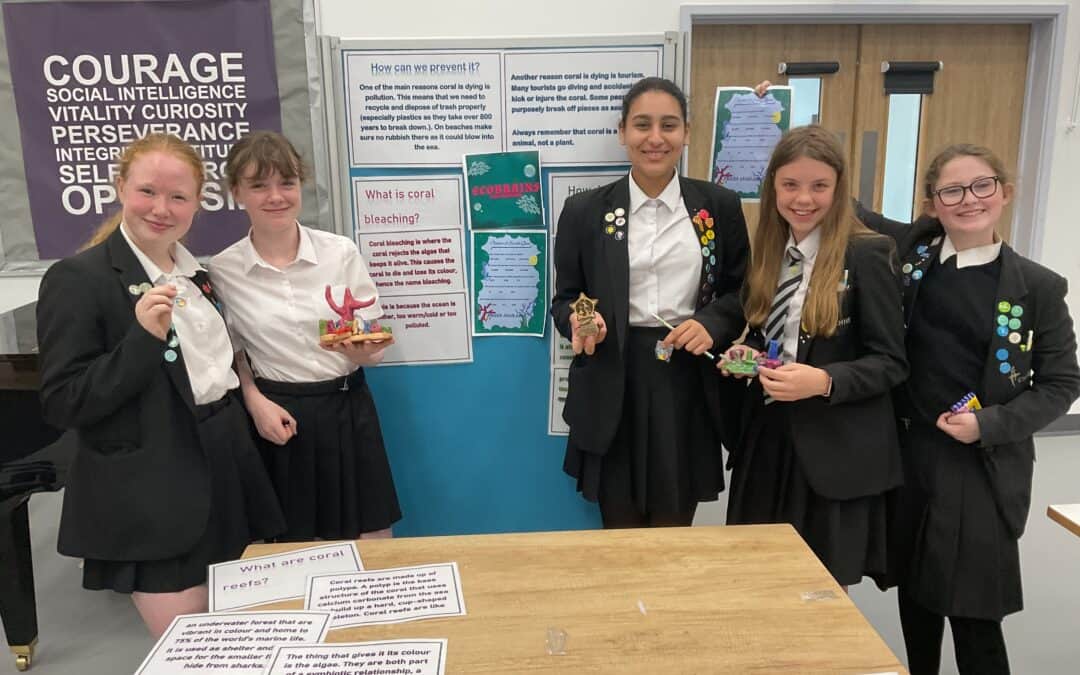 The five Cheadle Hulme High School students from Team Eco Brains, the winners of the Laurus Trust Science Fair 2023, stand smiling with their project at Laurus Cheadle Hulme.