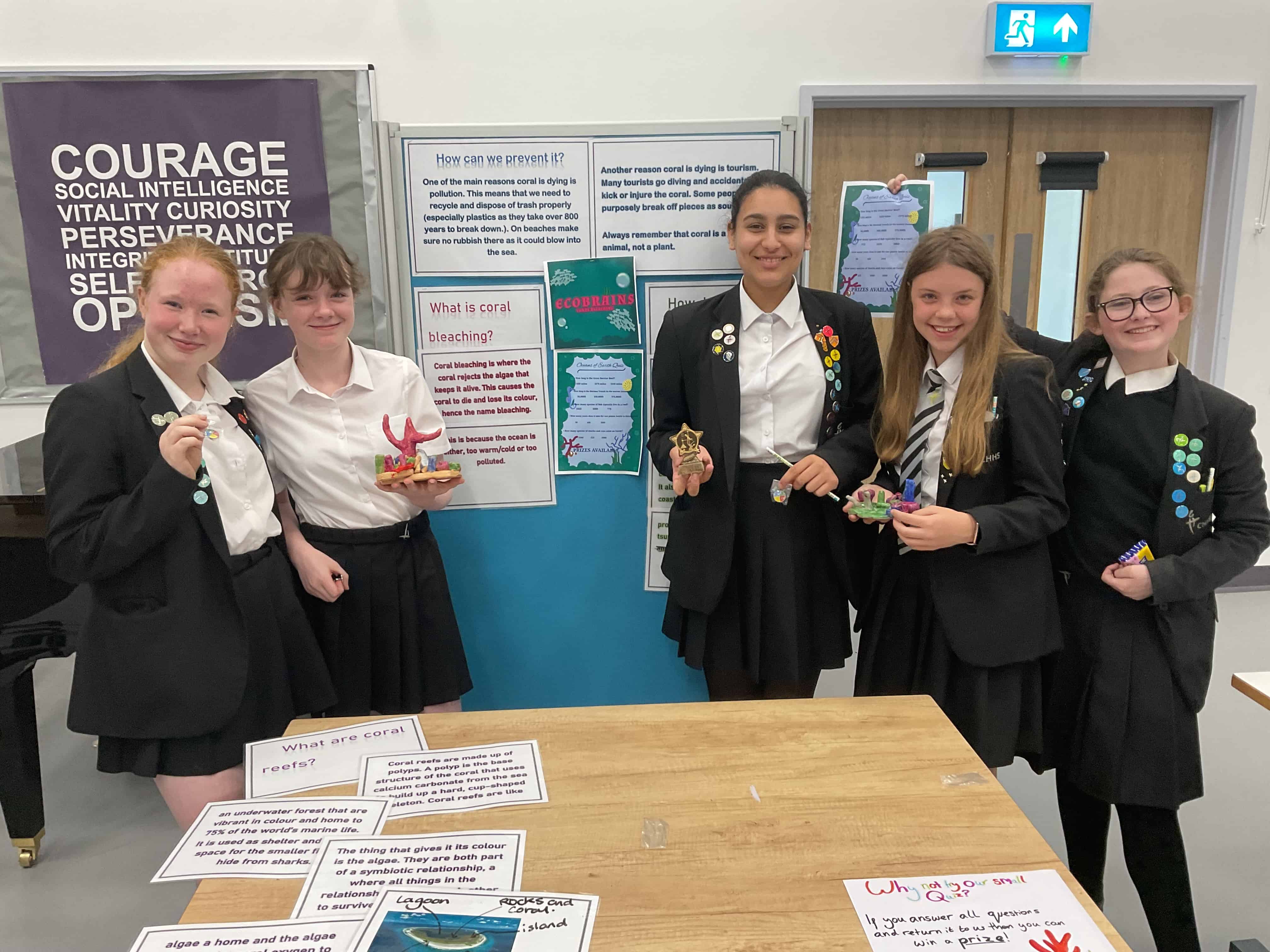 The five Cheadle Hulme High School students from Team Eco Brains, the winners of the Laurus Trust Science Fair 2023, stand smiling with their project at Laurus Cheadle Hulme.