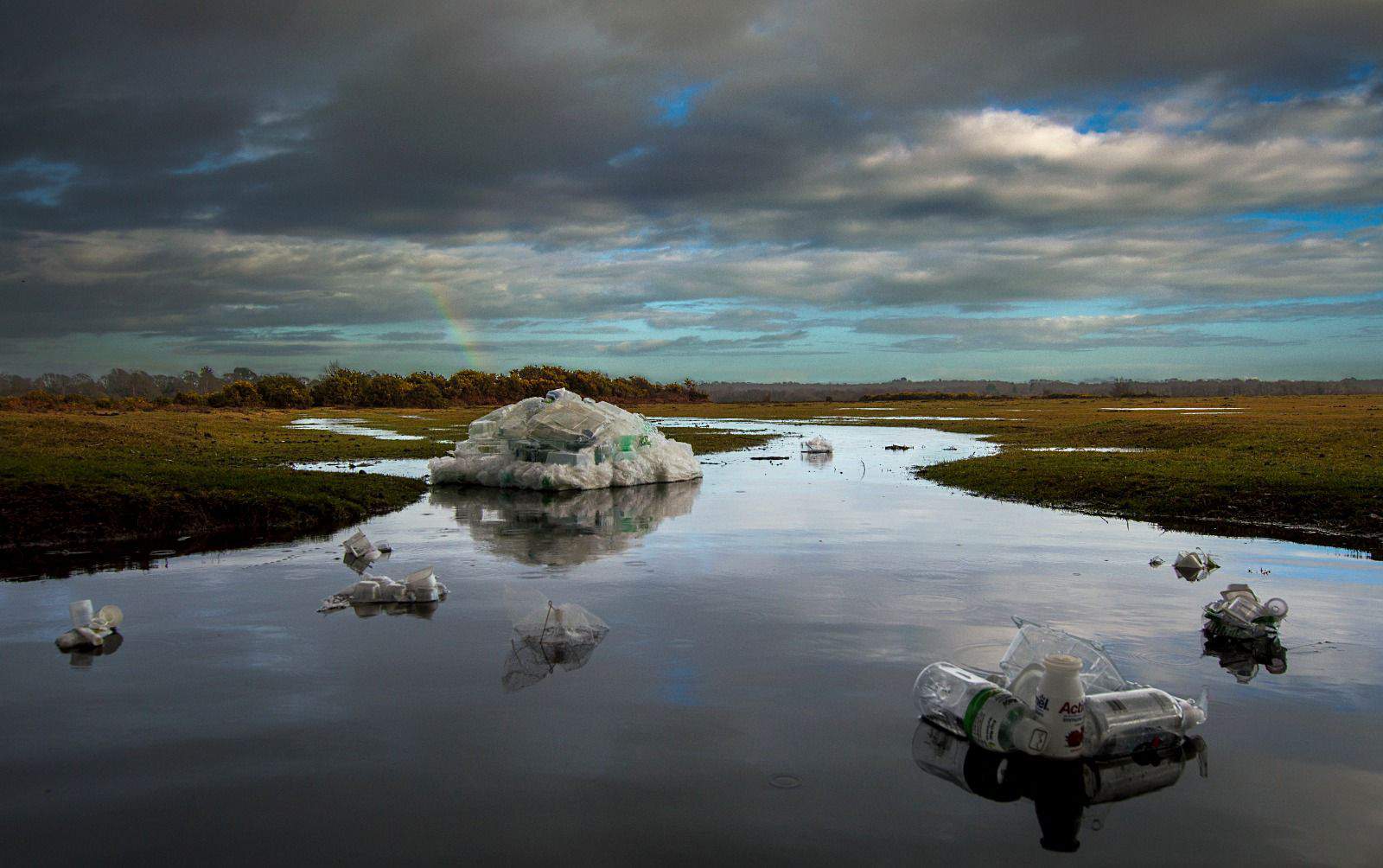 An image of a swampy grass field, full of piles of plastic in the water. A rainbow can be seen in the clouds. Taken by Rachel in Year 7, the overall runner up in Cheadle Hulme High School Photography Calendar Competition 2024.