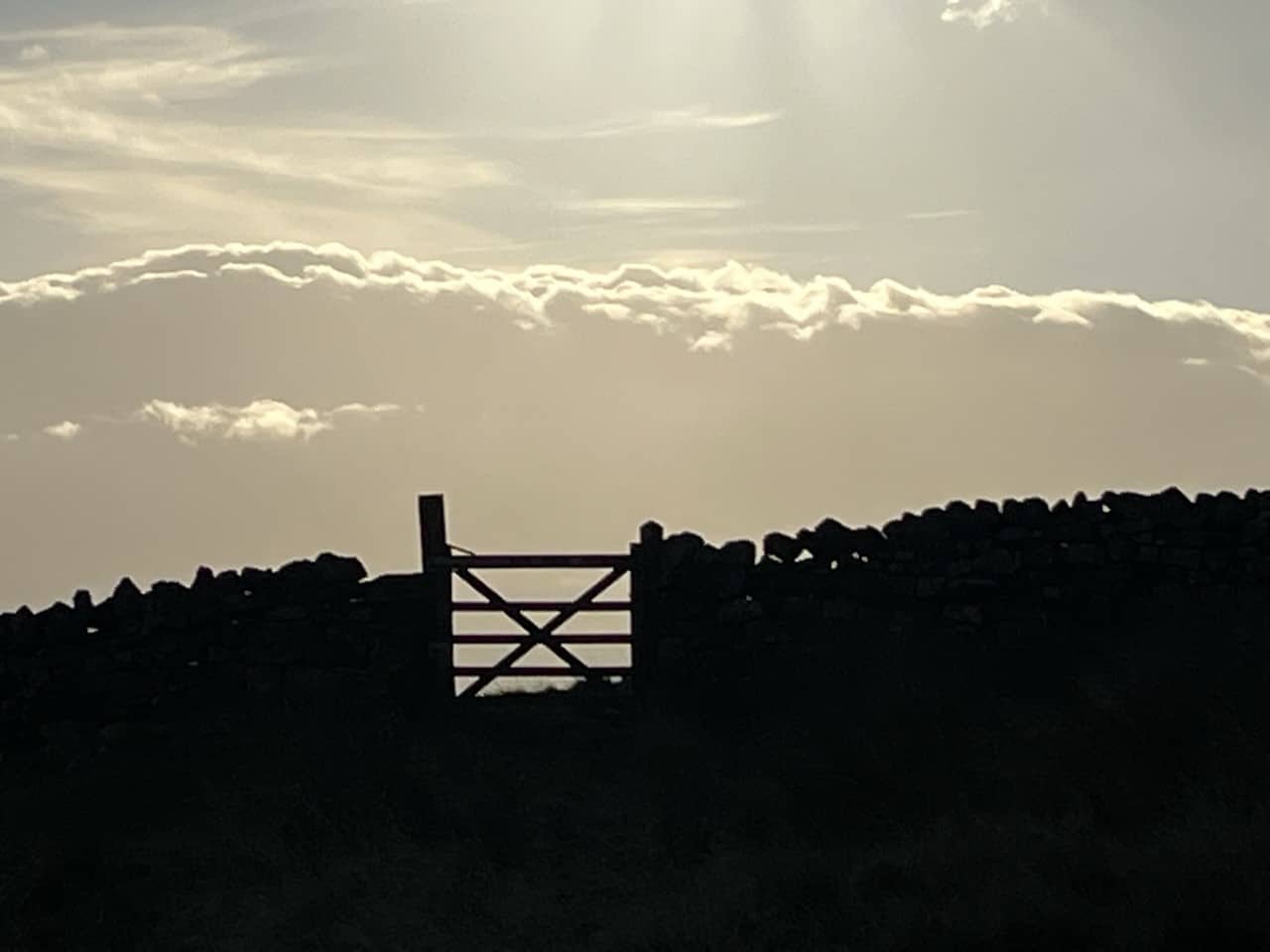 A A brick wall and gate silhouetted against a sunset in the countryside